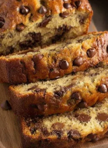 Slice of chocolate chip banana bread on a wooden cutting board