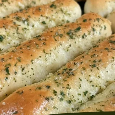 Homemade Olive Garden breadsticks served with marinara sauce.