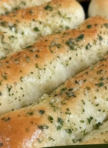 Homemade Olive Garden breadsticks served with marinara sauce.