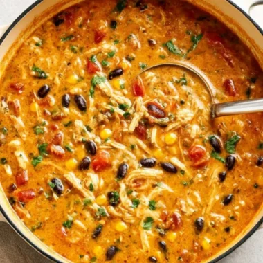 Bowl of creamy chicken tortilla soup topped with crispy tortilla strips and cilantro