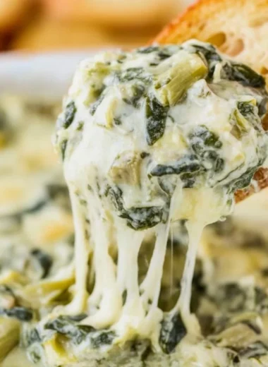Creamy spinach artichoke dip served in a bowl with fresh veggies
