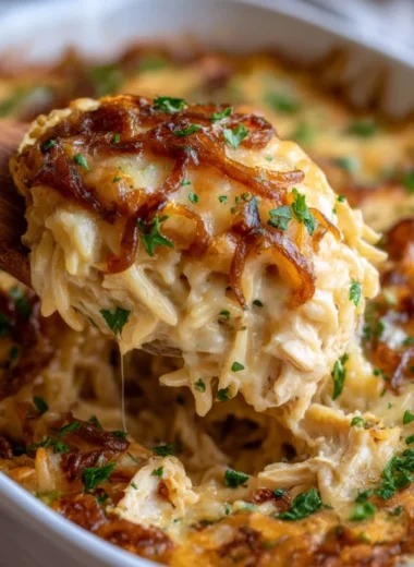 Delicious French Onion Chicken Orzo Casserole topped with cheese and herbs.