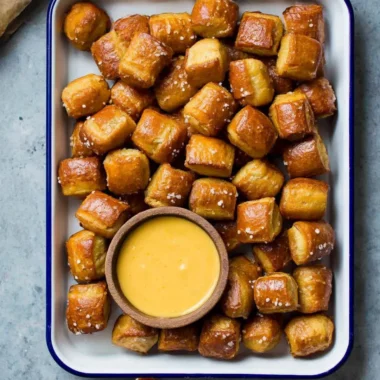 Bowl of homemade soft pretzel bites with dipping sauce on a wooden table