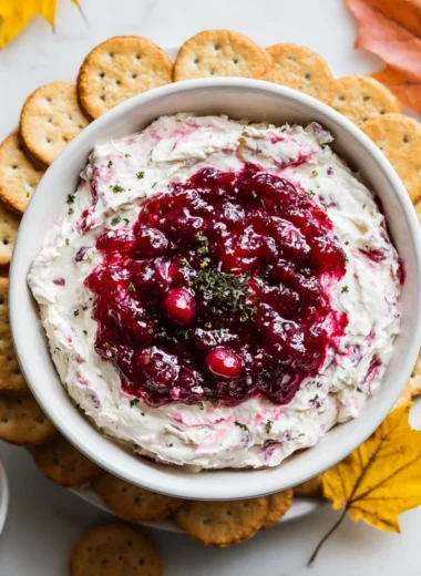 Cranberry Cream Cheese Dip served in a bowl with crackers and fresh cranberries