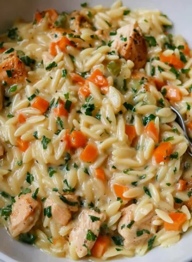 Creamy chicken pot pie orzo served in a bowl with fresh herbs