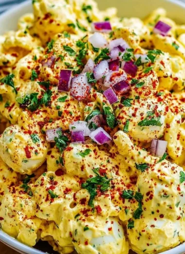 Creamy deviled egg macaroni salad in a bowl with fresh herbs