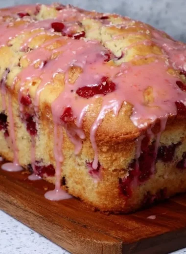Freshly baked glazed strawberry bread on a wooden table