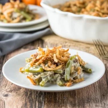 Delicious green bean casserole served in a white dish with crispy onions on top.