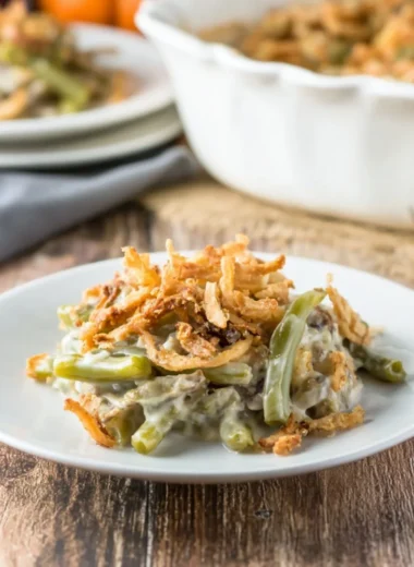 Delicious green bean casserole served in a white dish with crispy onions on top.