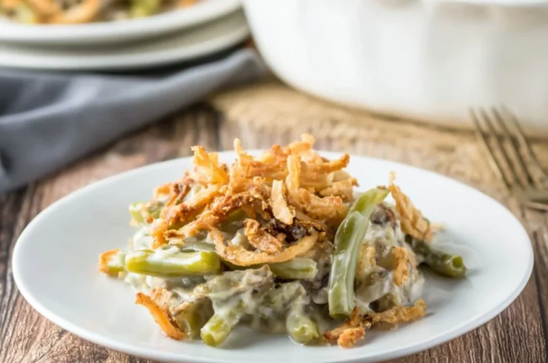 Delicious green bean casserole served in a white dish with crispy onions on top.