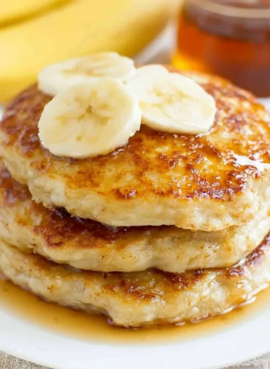 Fluffy banana pancakes stacked with syrup and fresh bananas on top.