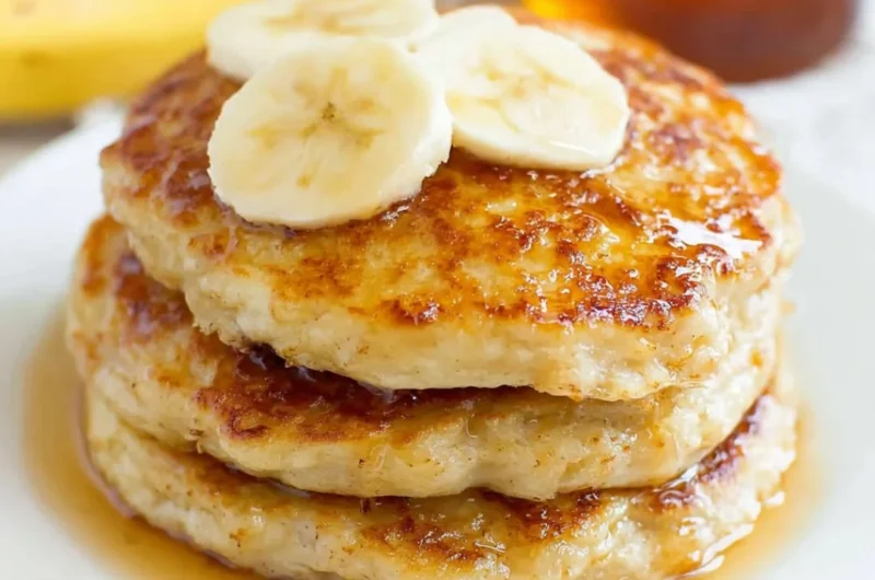 Fluffy banana pancakes stacked with syrup and fresh bananas on top.