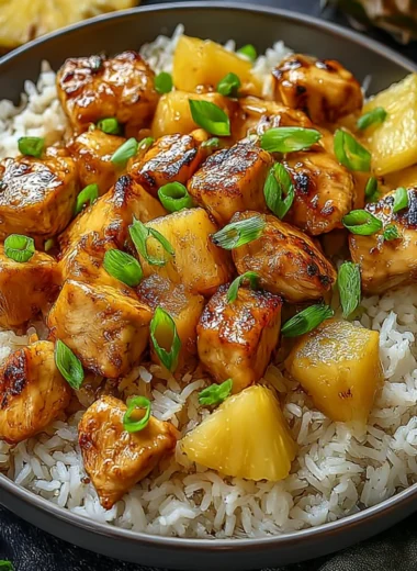 Plate of Pineapple Chicken served with rice and garnished with green onions