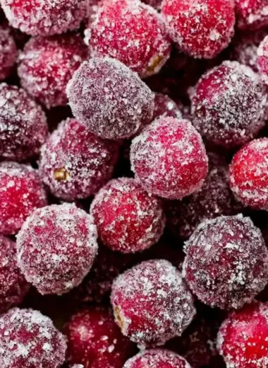 Bowl of sugared cranberries glistening with sugar, perfect for holiday decoration.
