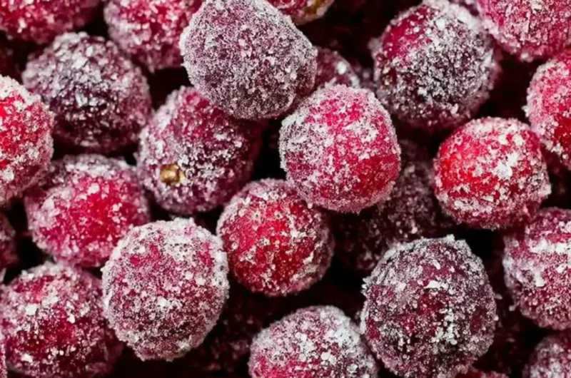 Bowl of sugared cranberries glistening with sugar, perfect for holiday decoration.