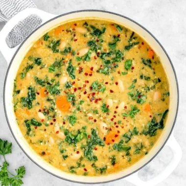 A bowl of Tuscan White Bean Soup garnished with herbs and served with crusty bread.