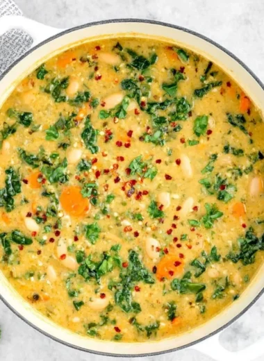 A bowl of Tuscan White Bean Soup garnished with herbs and served with crusty bread.