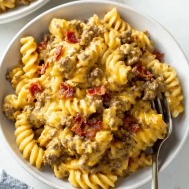 Delicious plate of cheeseburger pasta topped with melted cheese and garnishes.