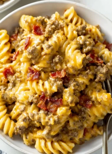 Delicious plate of cheeseburger pasta topped with melted cheese and garnishes.
