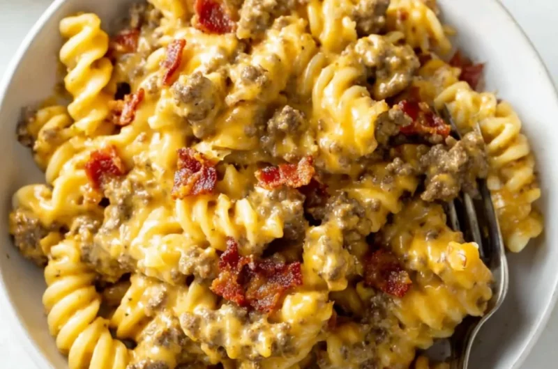 Delicious plate of cheeseburger pasta topped with melted cheese and garnishes.