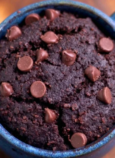 A delicious chocolate brownie mug cake served in a mug with a spoon.