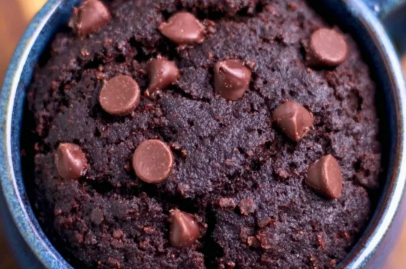 A delicious chocolate brownie mug cake served in a mug with a spoon.