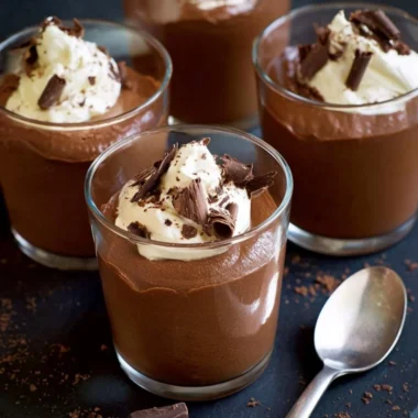 A bowl of healthy chocolate mousse topped with fresh berries and mint leaves.