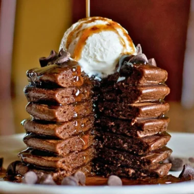 Delicious chocolate protein pancakes stacked with syrup and fruit on top
