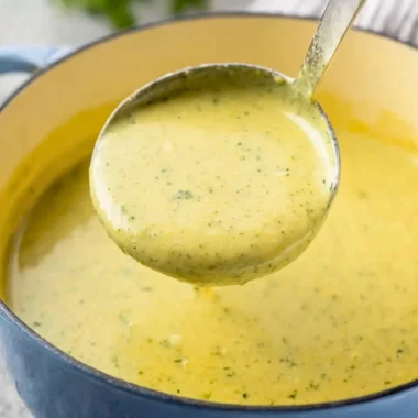 Bowl of creamy zucchini soup garnished with fresh herbs and served with bread