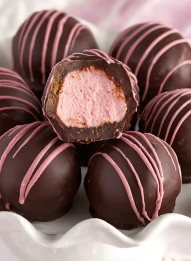 Decadent chocolate raspberry truffles topped with cocoa powder on a wooden background