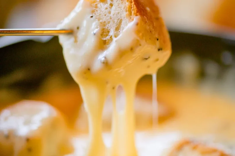 Bowl of easy cheese fondue with bread and vegetables for dipping