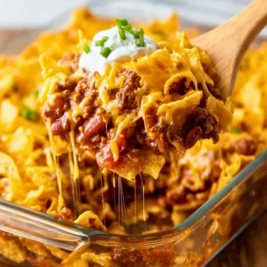 Delicious homemade Frito Pie served in a bowl, topped with cheese and jalapeños.