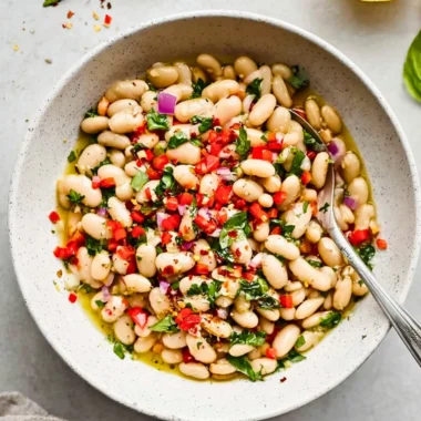 Bowl of Italian marinated white beans garnished with herbs.