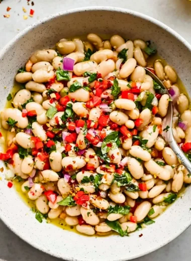 Bowl of Italian marinated white beans garnished with herbs.