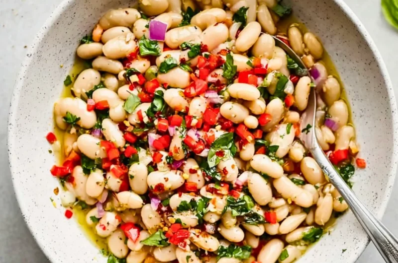 Bowl of Italian marinated white beans garnished with herbs.