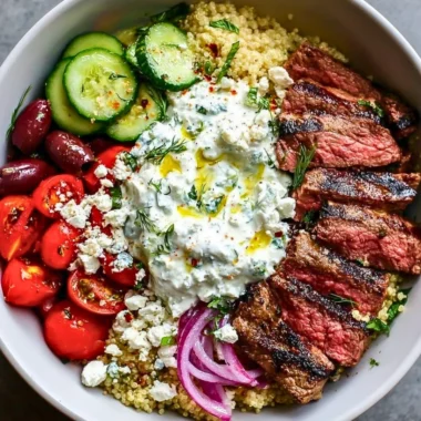 Mediterranean steak bowl topped with fresh vegetables and herbs