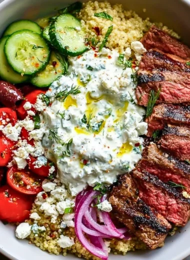 Mediterranean steak bowl topped with fresh vegetables and herbs