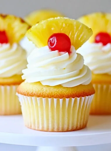 Delicious pineapple cream cupcakes topped with fluffy frosting and fresh fruit.