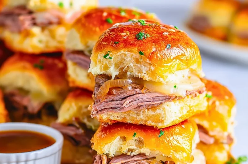 Delicious French Dip Sliders with beef, cheese, and au jus in a serving platter.