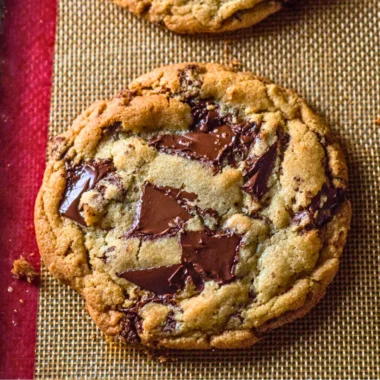 Freshly baked giant chocolate chip cookies piled on a plate