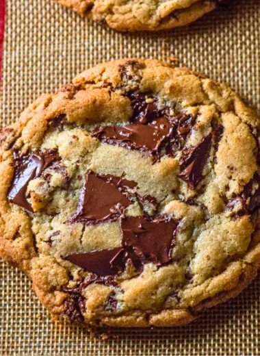 Freshly baked giant chocolate chip cookies piled on a plate