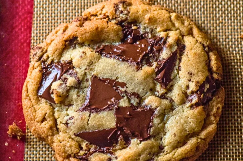 Freshly baked giant chocolate chip cookies piled on a plate