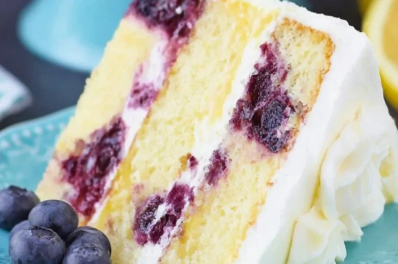 Slice of moist Lemon Blueberry Cake topped with fresh blueberries and lemon zest.
