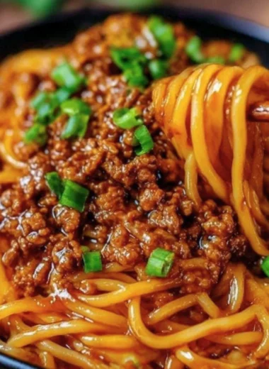 Delicious plate of Mongolian Ground Beef Noodles garnished with green onions.
