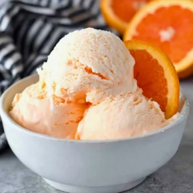 Delicious homemade orange ice cream served in a bowl with fresh orange slices