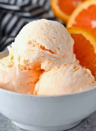 Delicious homemade orange ice cream served in a bowl with fresh orange slices