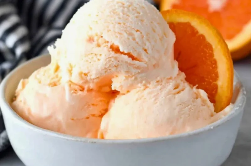 Delicious homemade orange ice cream served in a bowl with fresh orange slices