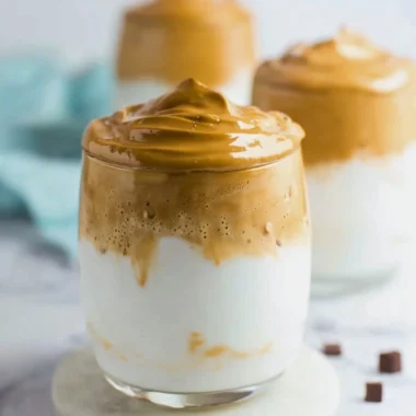 A frothy cup of whipped coffee topped with creamy foam and a sprinkle of cocoa