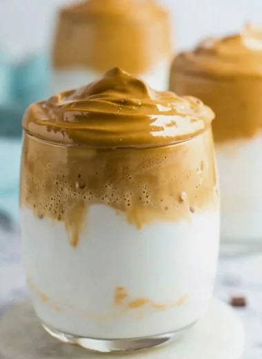 A frothy cup of whipped coffee topped with creamy foam and a sprinkle of cocoa