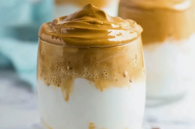 A frothy cup of whipped coffee topped with creamy foam and a sprinkle of cocoa